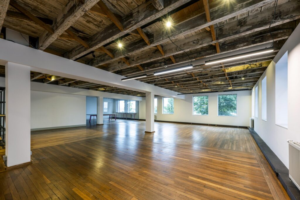 Ruime, lichte verdieping aan de De Ruijterkade met houten vloer, industriële plafondbalken en grote ramen.